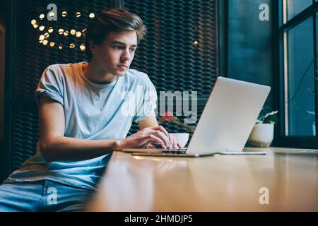 Focused freelancer using laptop for working in modern cafeteria Stock Photo
