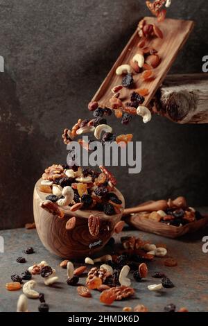 Falling wooden dish with nuts and raisins. Selective focus. Stock Photo