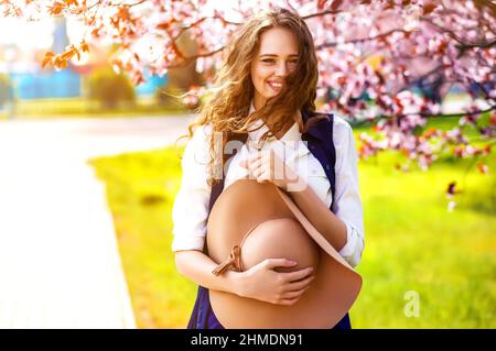 Outdoor portrait of young beautiful fashionable lady posing near flowering tree.  Stock Photo