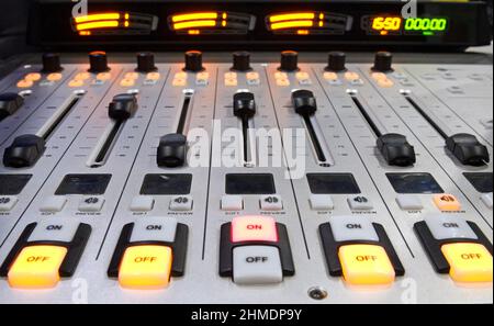 Buttons, volume levels, switches on the audio mixer control panel working on a table at the radio studio Stock Photo