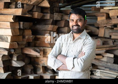 Confident smiling carpenter with arms crossed standing by looking at camera - concept of self confidence, skilled professional occupation and Stock Photo