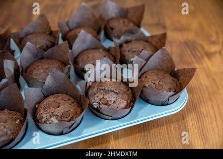 Chocolate muffins in brown baking paper cup from above. Close-up of brown cupcakes with chocolate drops. Stock Photo