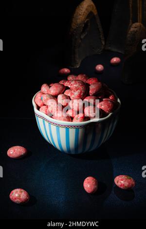 Chocolate dragees in crispy colored glaze. Dragee with almonds in a vase. Colorful candies on the table. Stock Photo