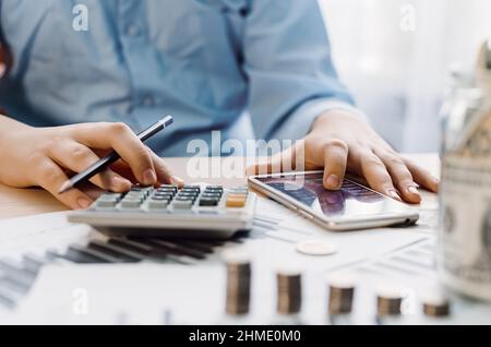 Businessman using calculator for analysis maketing plan, Accountant calculate financial report, computer with graph chart. Business, Finance and Accou Stock Photo