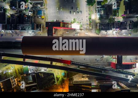 top down flat aerial shot showing red roof of elevated metro train station with track coming out over busy street with cars in bangalore gurgaon india Stock Photo