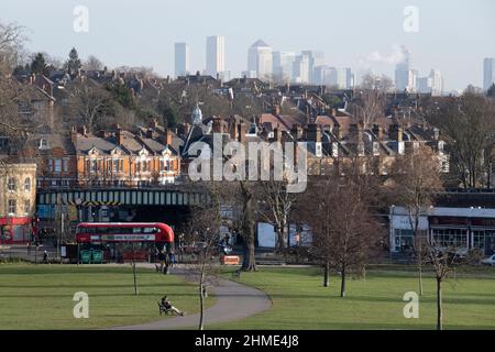 Park users in Brockwell Park in Herne Hill, SE24 and in the distance, the high-rises of Canary Wharf in London Docklands, on 7th February 2022, in London, England. Stock Photo