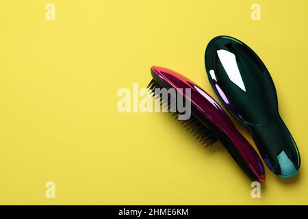 Colored plastic hair brushes on yellow background Stock Photo