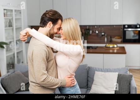 Bearded man and charming caucasian woman is dancing in a new empty house. Caucasian couple in love at moving day in rent apartment, own habitation Stock Photo