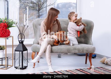mothers day. Portrait of little preschool girl kid young mother have fun playing and having fun together with teddy bears at home, mom and daughter sh Stock Photo