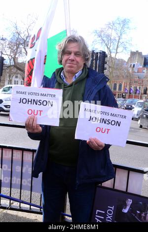 London, UK, 9th February, 2022. An anti brexit protester holds a placard critical of UK Prime Minister Boris Johnson and calling for him to leave office across the road from the House of Commons. Stock Photo