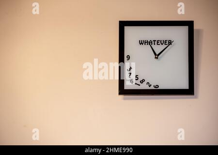 a square clock without numbers hangs on the wall. A watch with an inscription whatever. Stock Photo