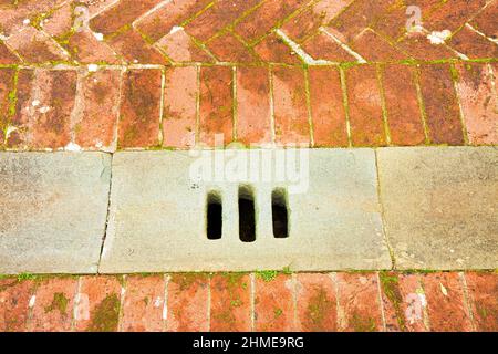 Old brick floor of the Tuscan tradition (Italy) with manhole stone in the foreground Stock Photo