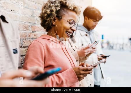 Addicted diverse young people using mobile phone outdoors Stock Photo