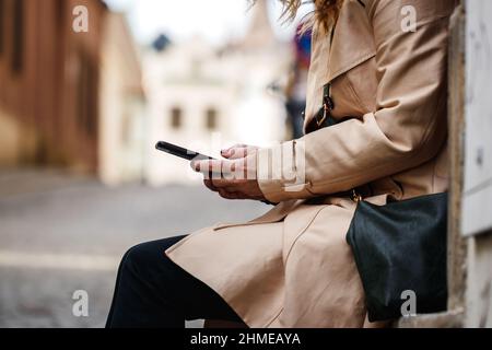 Woman text messaging on her smartphone at city street. Mobile phone in female hand Stock Photo