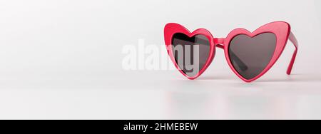Banner with heart-shaped sun glasses. Valentines red sunglasses on background with copy space. High quality photo Stock Photo