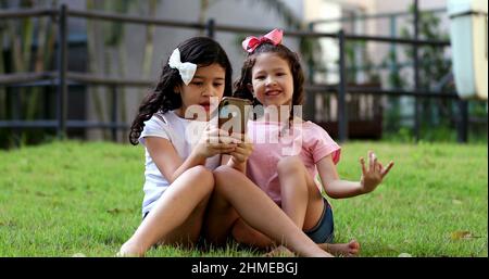 Children addicted to cellphone, two little girls looking at smartphone ...