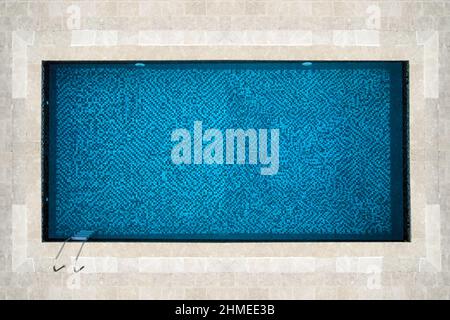 top view of a beautiful idyllic rectangular swimming pool with blue mosaic at the bottom Stock Photo