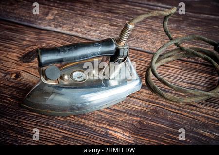 Vintage old-fashioned electric iron for clothes with wooden handle and cord  on wooden background Stock Photo - Alamy
