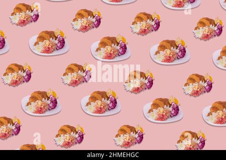 Creative pattern made of freshly baked croissant with various colorful flowers on pastel pink background. Minimal spring or summer concept. Modern fun Stock Photo