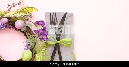 Easter table setting. Pastel color wreath with egg and flower decoration on pink background, top view, copy space. Spring Holiday celebration. Stock Photo