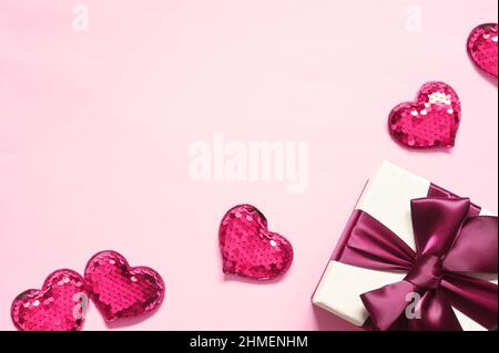 Top view photo of valentine's day decorations. White gift box with pink ribbon bow and small hearts on isolated pink background with empty space. Stock Photo