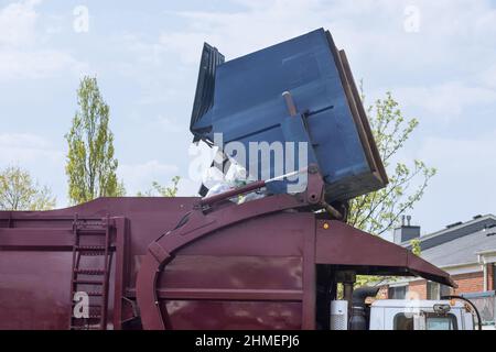 Municipal waste disposal with a special car garbage truck, the garbage bin is loaded into car. Stock Photo