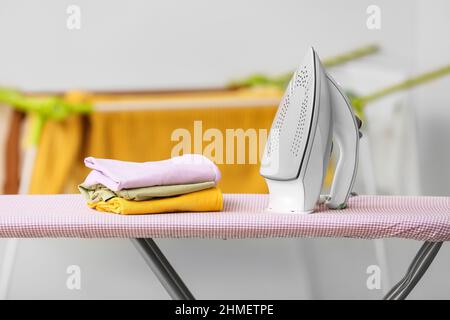 Stack of clothes and electric iron on board Stock Photo