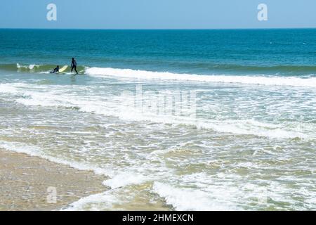 Surfers in landscape at Sea Girt beach in New Jersey USA Stock Photo