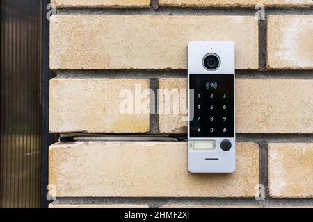 an intercom on the door of a private house, an intercom panel with a video camera on a brick beige fence post of a private house. Stock Photo