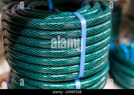 new green garden watering hose wound into a bay. Stock Photo