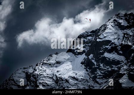 Two paragliders over snowy peak with dramatic clouds, Sellrain, Innsbruck, Tyrol, Austria Stock Photo