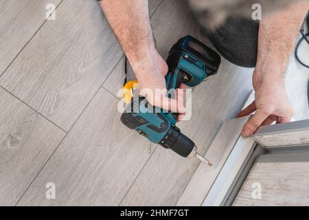 One unknown man caucasian male using electric cordless screwdriver drill assembling furniture at home DIY carpenter at work close up on hands copy spa Stock Photo