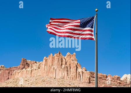 US flag fluttering against a blue sky, behind it the rock formation The Castle, Capitol Reef National Park, Utah, USA Stock Photo