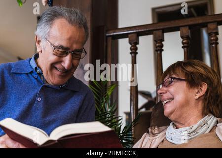 Grandparents reading a book sited in house Stock Photo
