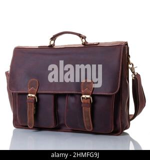 Brown leather briefcase with pockets. One handle and shoulder strap. Flap with fasteners. Brass fittings Stock Photo