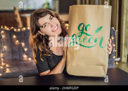 Go green. Calligrapher Young Woman writes phrase on white paper. Inscribing ornamental decorated letters. Calligraphy, graphic design, lettering Stock Photo