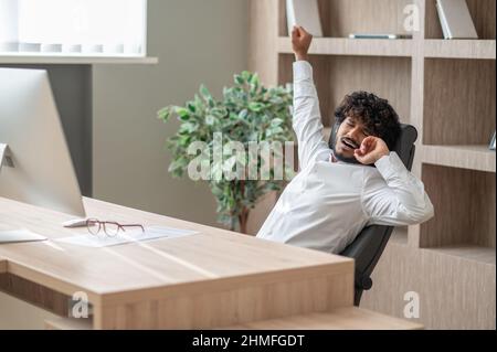 Dark-haired businessman feeling sleepy and stretching Stock Photo