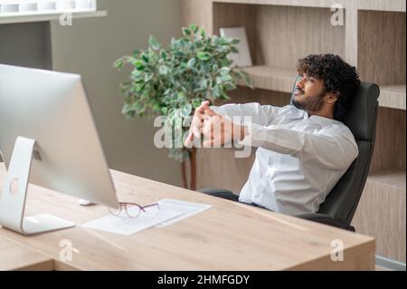 Dark-haired businessman feeling sleepy and stretching Stock Photo