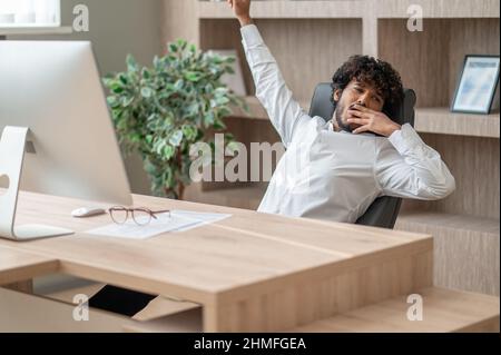 Dark-haired businessman feeling sleepy and stretching Stock Photo