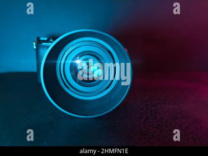 Professional Photography Digital Camera And Lens On Black Surface With Colored Lighting Stock Photo