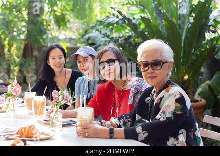 Asian senior woman and adult daughter drinking coffee at cafe outdoor. Stock Photo