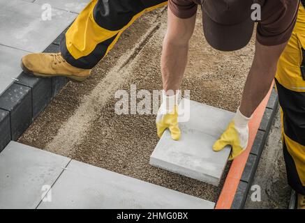 Caucasian Professional Worker in His 40s Building Large Concrete Bricks Garden Path. Backyard Improvement Theme. Stock Photo