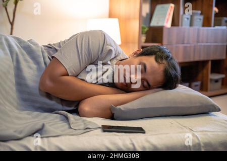 Young Asian man sleeping in bed Stock Photo