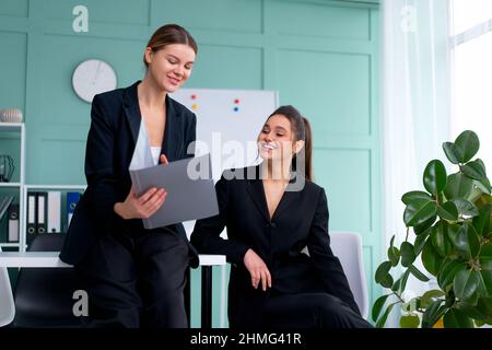Young women leaders are checking financial statements from paper documents. Two female confident business worker dressed black suit in office checking Stock Photo