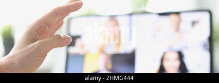 Female hand on background of tablet with video call from employees Stock Photo