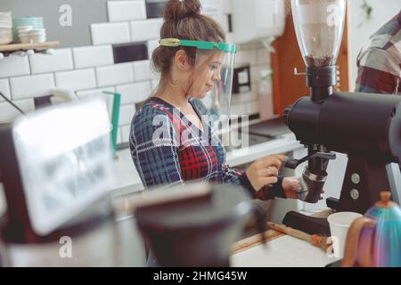 Portrait of focused barista grinding coffee beans in coffee grinder Stock Photo