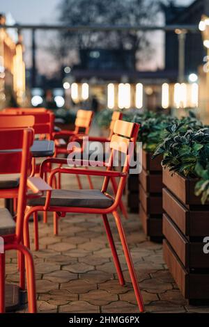 Empty chairs in outdoor cafe or restaurant on summer day. Empty tables of street cafe during lockdown, coronavirus quarantine. Stock Photo