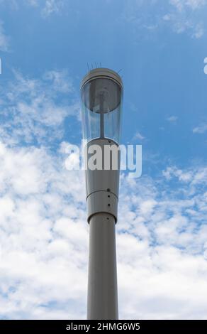 A typical small cell antenna for 5G wireless network installed on street lamp post isolated on blue sky. Street view, nobody, copyspace for text,