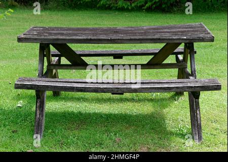A traditional wooden New Zealand picnic table may have seen better days but is still functional Stock Photo