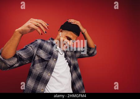 Cheerful young man enjoying his favourite music in a studio. Happy young man smiling while wearing wireless earphones. Handsome young man dancing whil Stock Photo